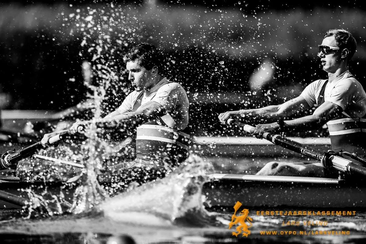 Two rowers competing, with water splashing around their boat.